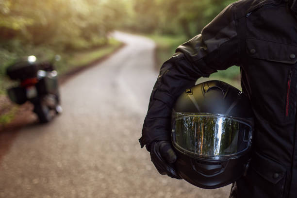 motard tenant un casque de moto avec sa moto en arrière plan dehors